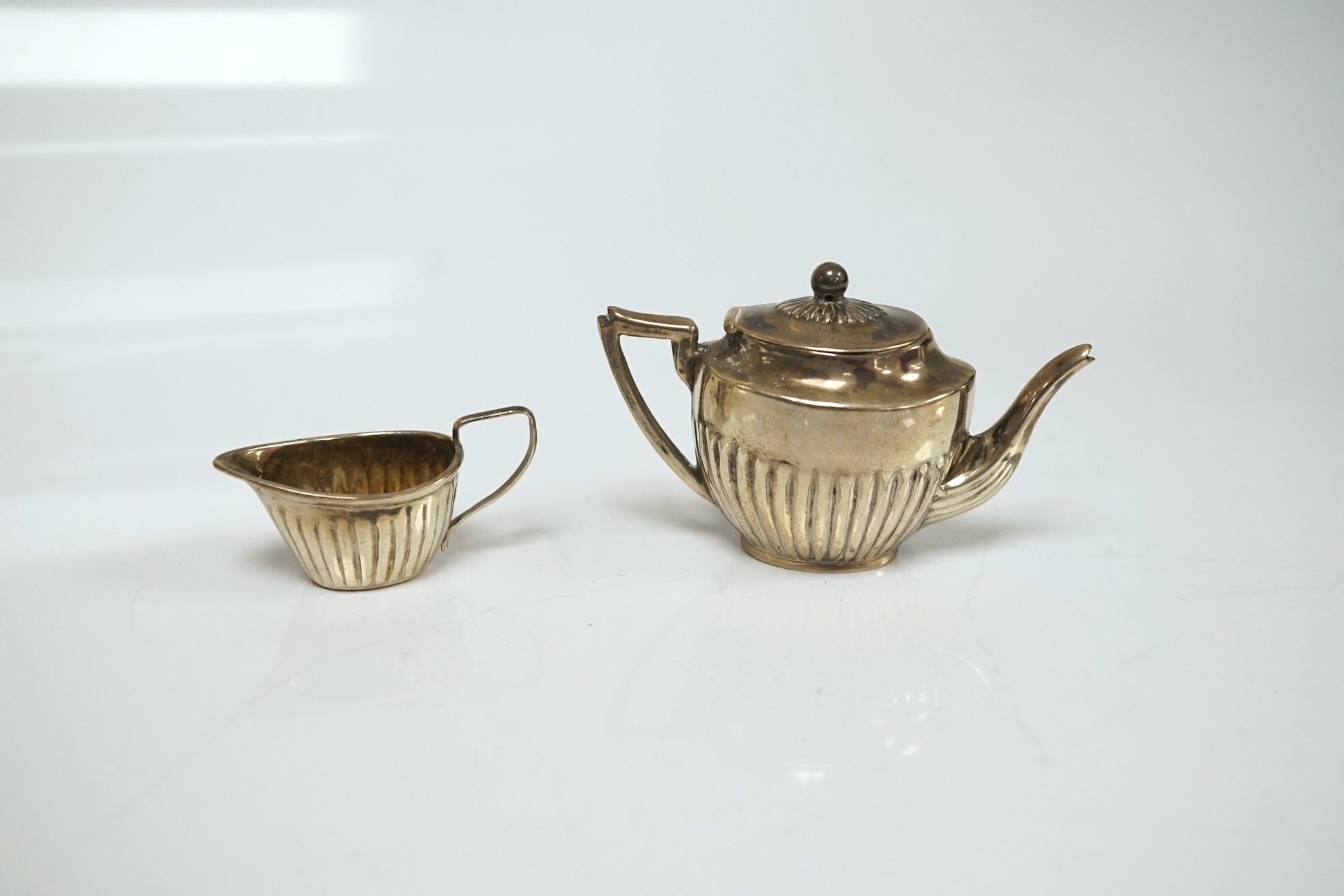 A collection of miniature silver including a three piece tea set and two handled tray by Saunders & Shepherd, Birmingham, 1904, tray 9.8cm, together with pepperettes including saucepan, candlesticks, hand mirror, etc. Co